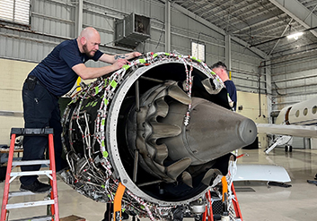 two aircraft mechanics fixing a jet engine